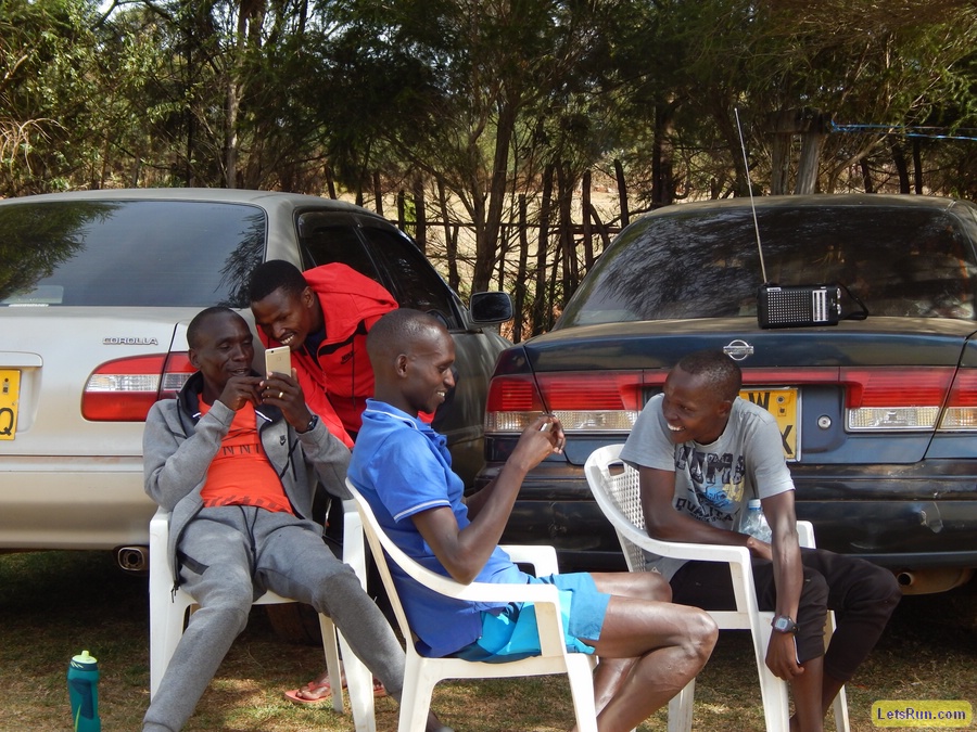 Kipchoge (seated) looking at his phone