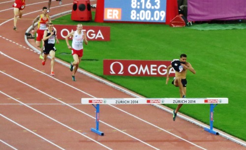 Mahiedine Mekhissi-Benabbad of France clearing the final barrier of the steeplechase at the 2014 European Championships in Athletics. He finished first, but was later disqualified for removing his shirt in the final 100 meters (photo by Jane Monti for Race Results Weekly)