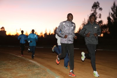 Eliud Kipchoge (r) warming up before sunset on the Moi University track