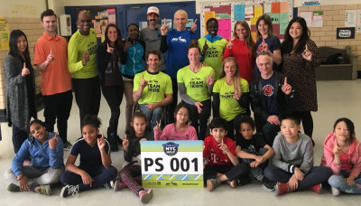 Liz Costello (third from right, back row) visiting Public School 1 in New York City in advance of the 2018 United Airlines NYC Half. Also in photo, NYRR president of events and race director Peter Ciaccia (back row, center, in blue shirt) and NYRR senior vice president for Youth & Community Services Rachel Pratt (back row, second from right). Photo courtesy of New York Road Runners